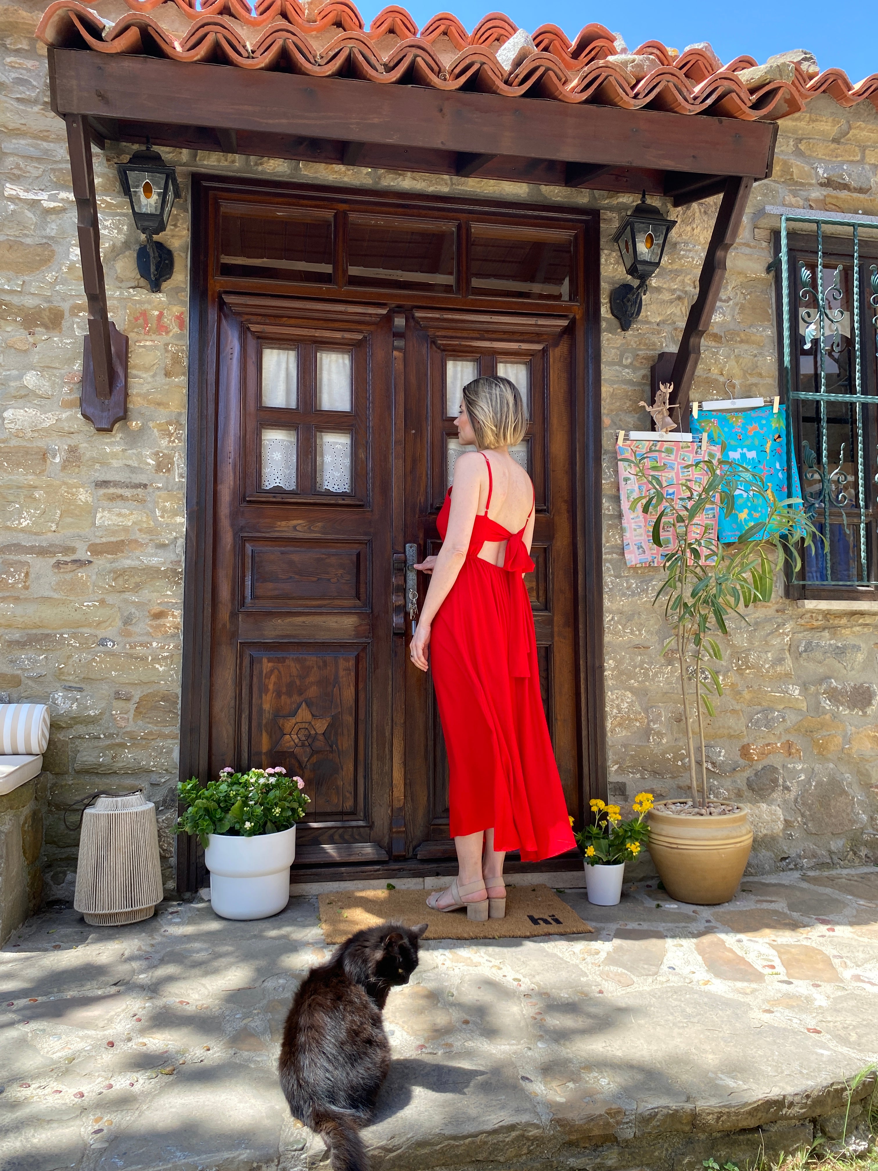 Doris red long dress in a summer outdoor setting by a stone house