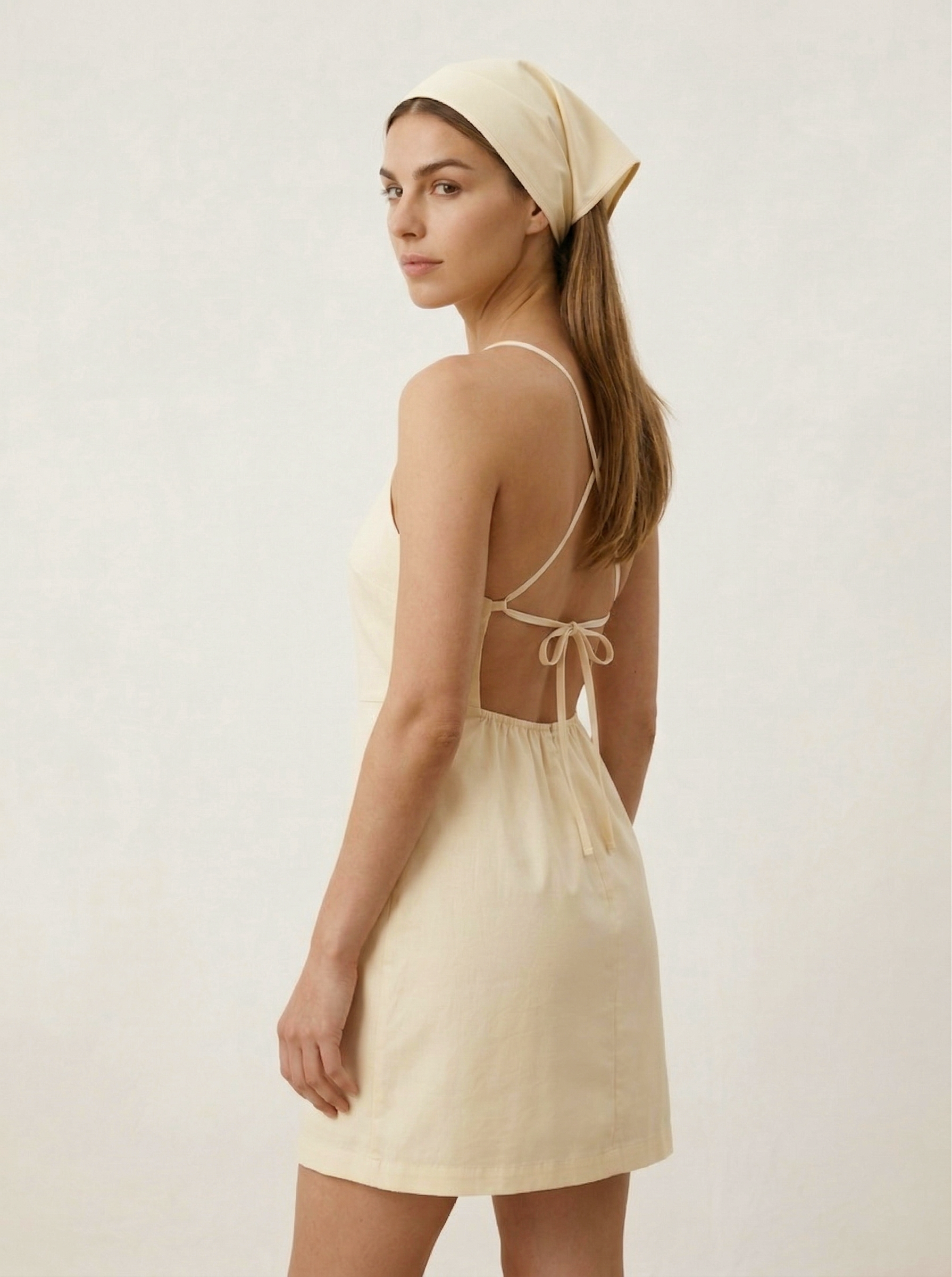 Butter yellow mini dress with adjustable cross back straps angled view
