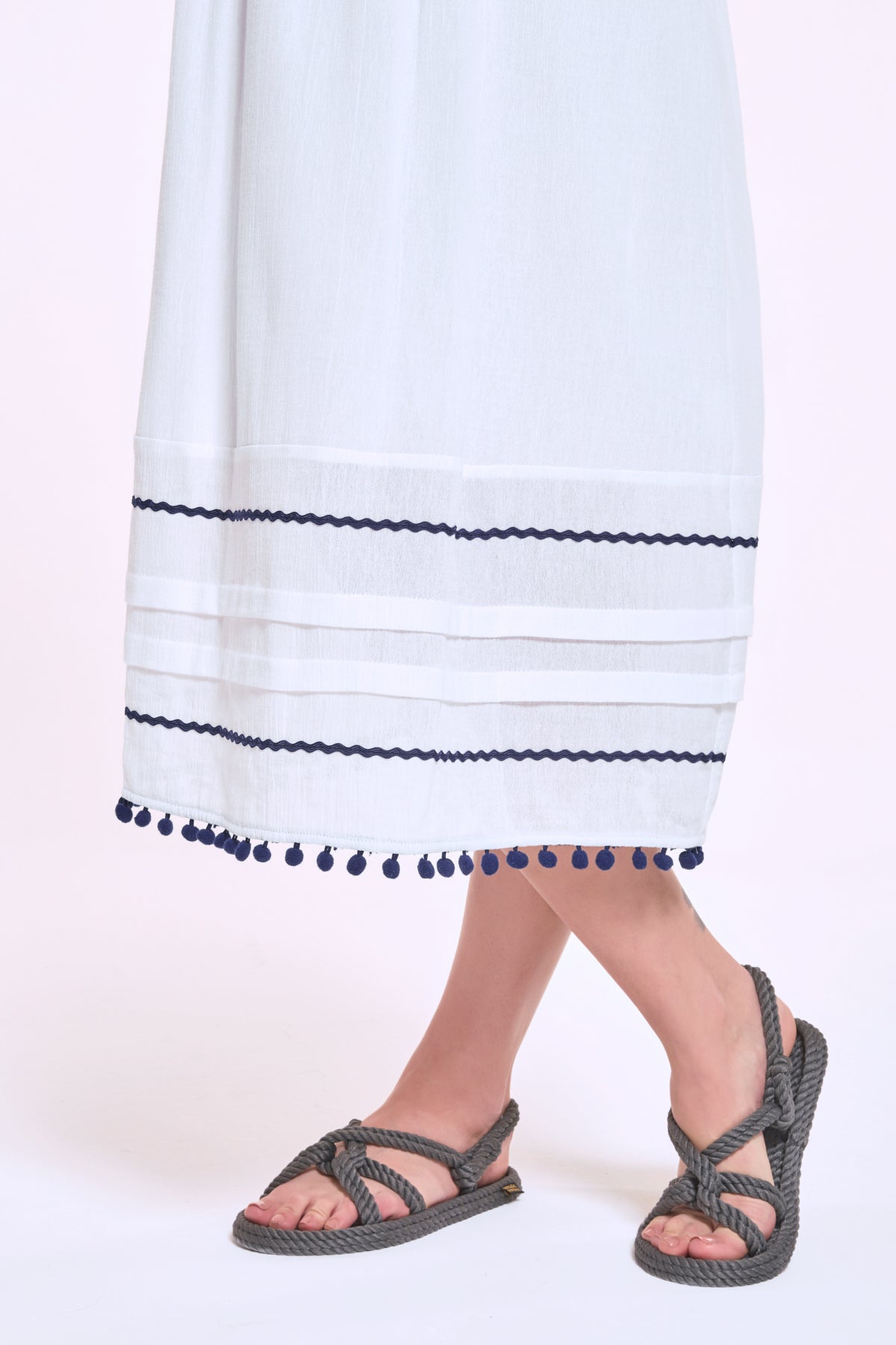 Hem detail with trim and pompom accents on Didi white dress